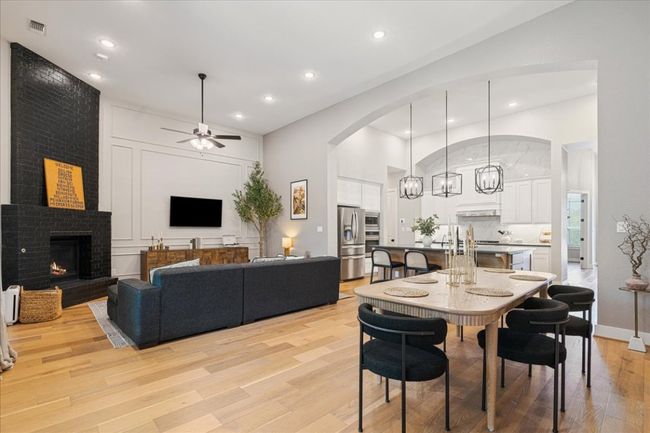 Dining space with light wood-type flooring, a ceiling fan, a fireplace, recessed lighting, and arched walkways | Image 15