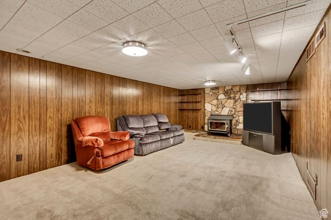 Carpeted living area with rail lighting, a wood stove, and wooden walls | Image 21