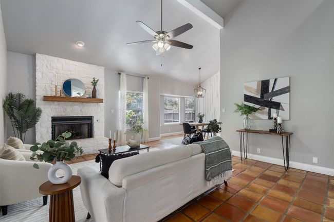 Tiled living room featuring ceiling fan, a fireplace, and high vaulted ceiling | Image 6