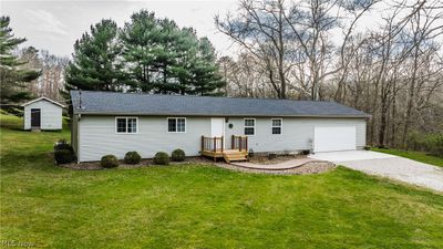 Single story home with a wooden deck, a front lawn, and a storage shed | Image 1