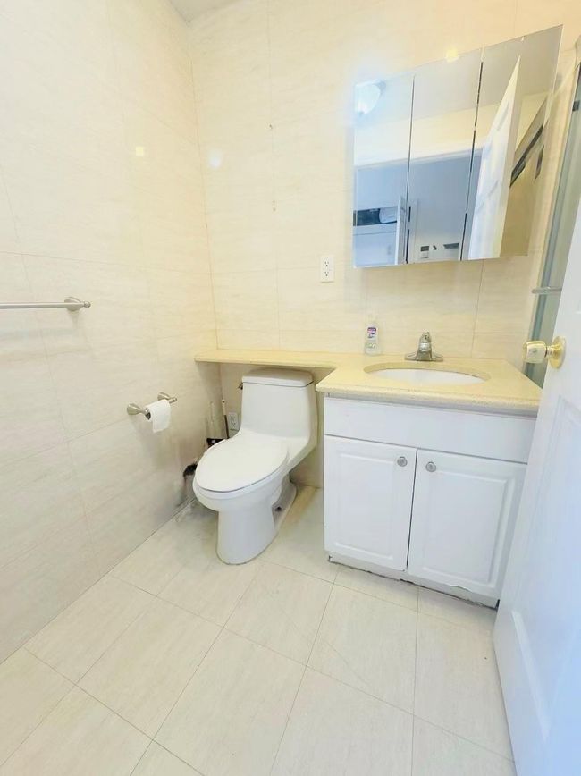 Bathroom with toilet, tile patterned flooring, vanity, and tile walls | Image 5