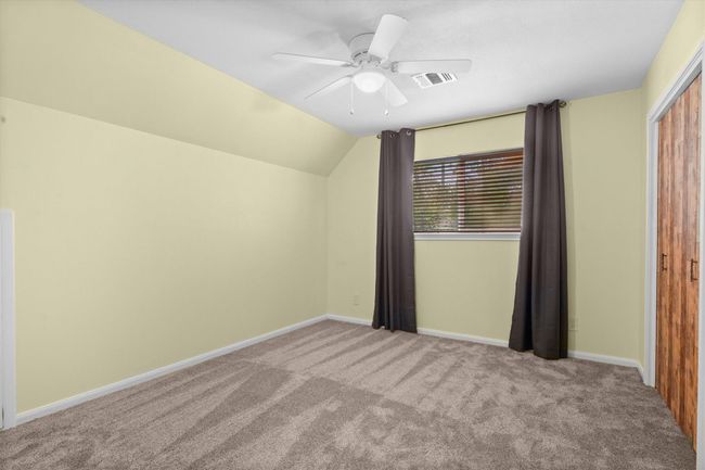 This room features soft yellow walls, plush carpet, a ceiling fan, and ample natural light through a window. It has a cozy and inviting atmosphere. | Image 34