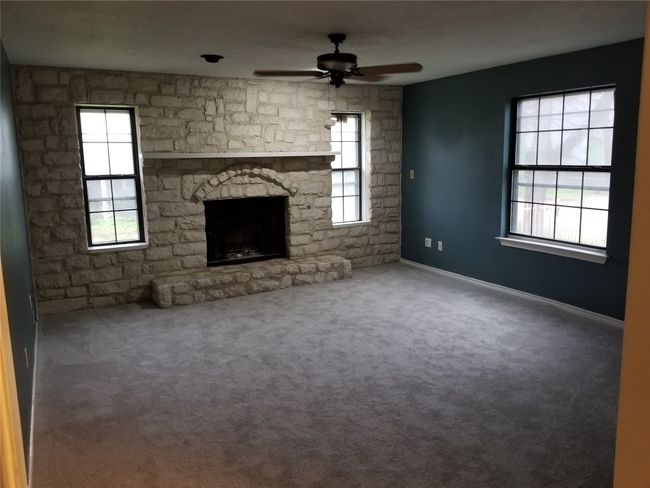 Unfurnished living room featuring ceiling fan, a fireplace, healthy amount of natural light, and carpet flooring | Image 8