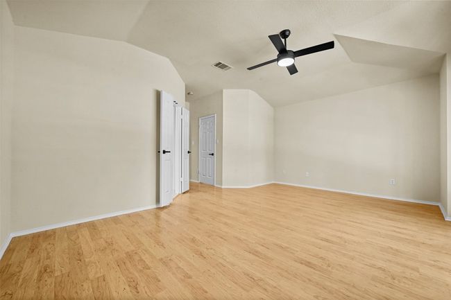 Empty room with vaulted ceiling, a ceiling fan, and light wood-style floors | Image 22