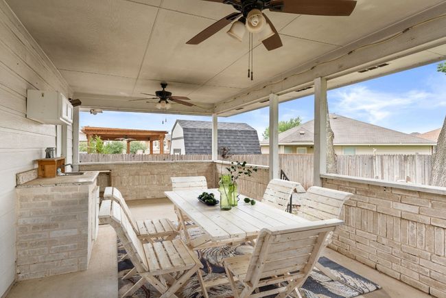 Photo virtually staged. View of patio / terrace with a sink, fence, a ceiling fan, and outdoor dining area | Image 28