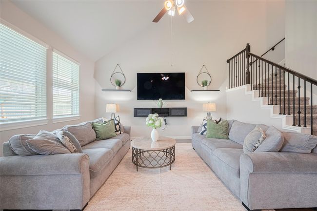 This inviting living room features high ceilings, large windows. A modern staircase leads upstairs, while a wall-mounted TV and elegant decor complete the space. Perfect for relaxation and entertainment. | Image 14