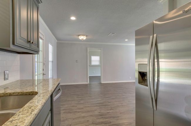 Kitchen with appliances with stainless steel finishes, gray cabinets, crown molding, a textured ceiling, and backsplash | Image 16