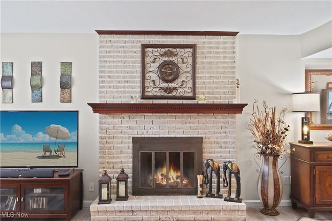 Room details featuring a brick fireplace, wood finished floors, and baseboards | Image 9