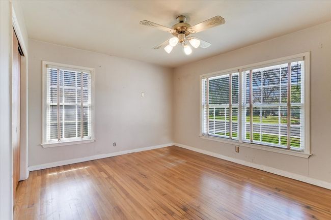 Empty room with light wood-type flooring, baseboards, and a ceiling fan | Image 5