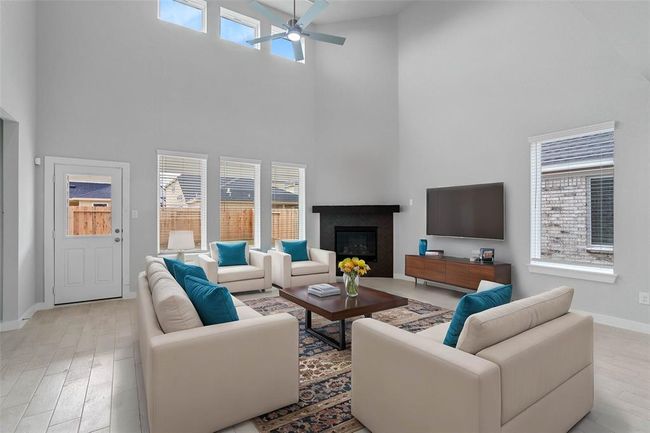 Gather the family and guests together in your lovely family room! Featuring a beautiful fireplace with wood mantel, high ceilings, ceiling fan, custom paint, gorgeous wood look floors and large windows that provide plenty of natural lighting throughout the day. | Image 8