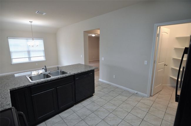 Kitchen with decorative light fixtures, black appliances, dark cabinetry, visible vents, and a sink | Image 14