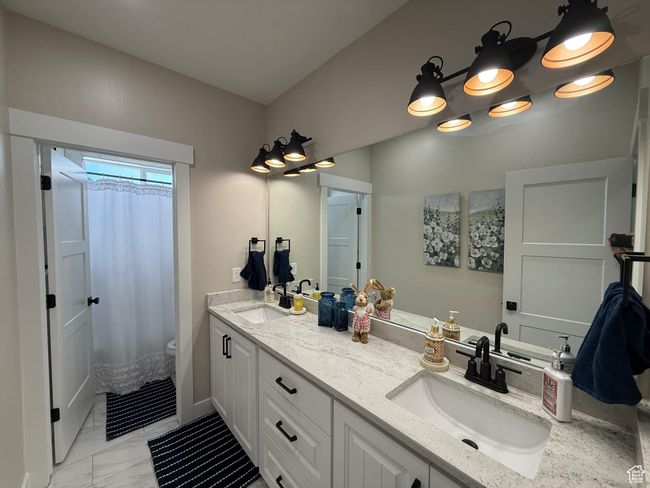 Bathroom with a shower with curtain, marble finish floor, a sink, and double vanity | Image 65