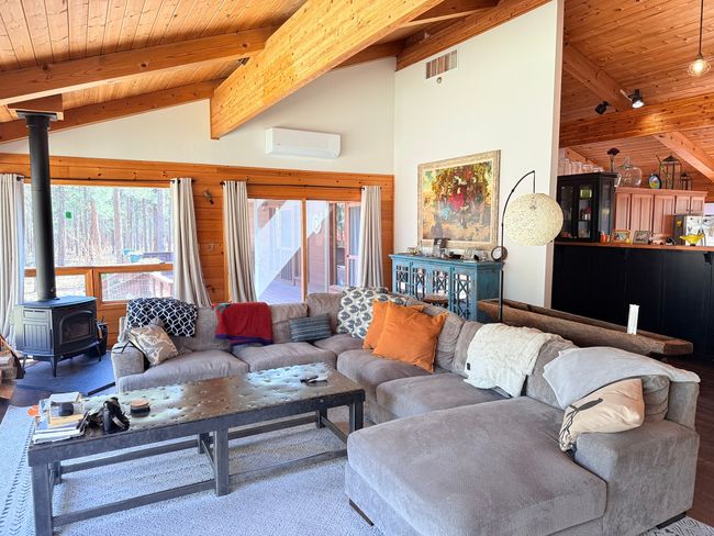 Living room with a wall mounted air conditioner, vaulted ceiling with beams, wood stove, and tongue & groove ceiling. Sofa included | Image 7