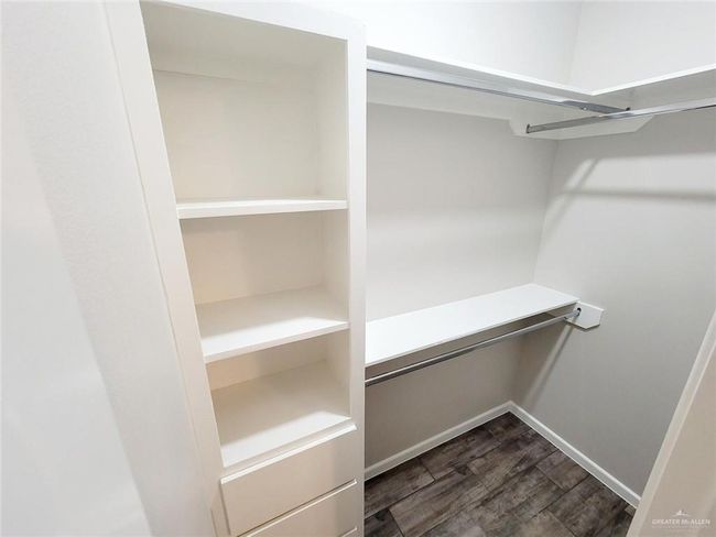 Spacious closet with dark wood finished floors | Image 7