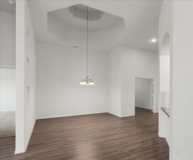 Unfurnished room featuring a tray ceiling, a chandelier, dark wood-type flooring, and baseboards | Image 17