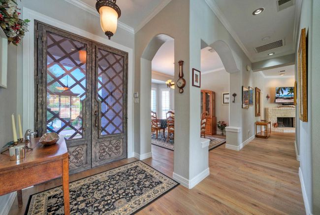 Foyer entrance with crown molding, visible vents, baseboards, arched walkways, and light wood-type flooring | Image 4