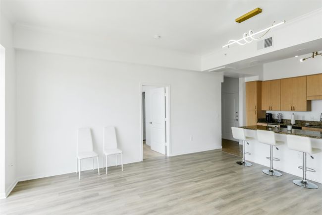 Kitchen featuring a kitchen breakfast bar, light wood-type flooring, dark stone countertops, pendant lighting, and brown cabinets | Image 17