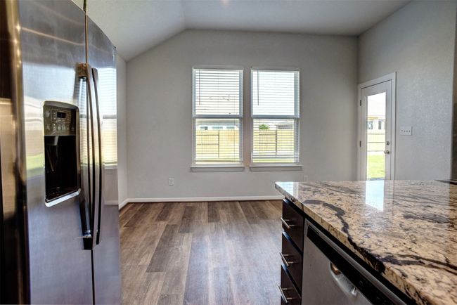 Kitchen with vaulted ceiling, stainless steel appliances, baseboards, light stone countertops, and dark wood-type flooring | Image 15