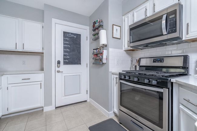 Kitchen with white cabinets, light countertops, backsplash, and appliances with stainless steel finishes | Image 13