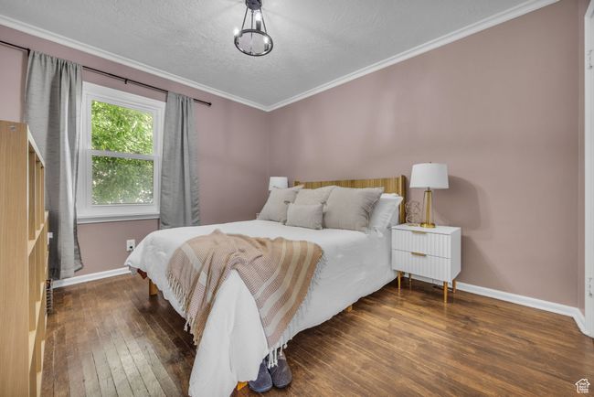 Bedroom featuring hardwood / wood-style floors, baseboards, a textured ceiling, and ornamental molding | Image 13