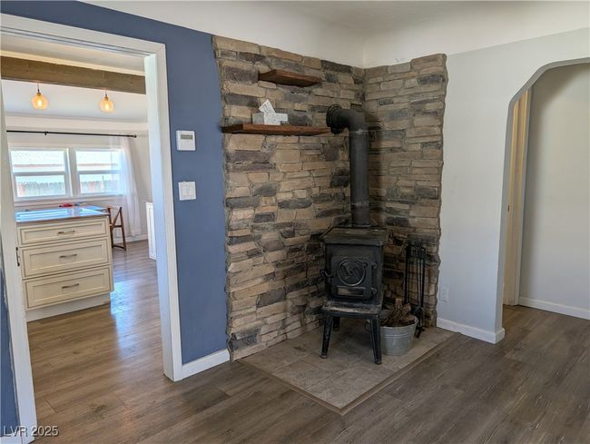 Room details featuring arched walkways, wood finished floors, a wood stove, and baseboards | Image 9