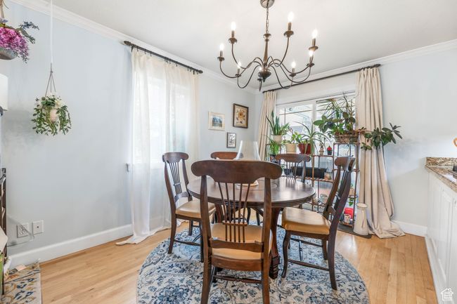 Dining area featuring baseboards, light wood finished floors, a chandelier, and crown molding | Image 7