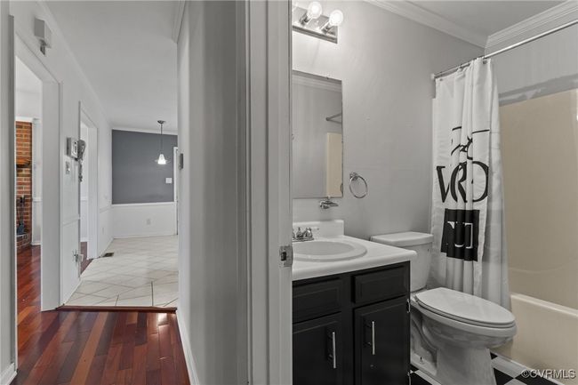 Full bathroom featuring shower / bath combo, toilet, wood finished floors, vanity, and ornamental molding | Image 18