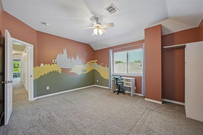 Carpeted bedroom with vaulted ceiling, an office area, baseboards, and a ceiling fan | Image 30