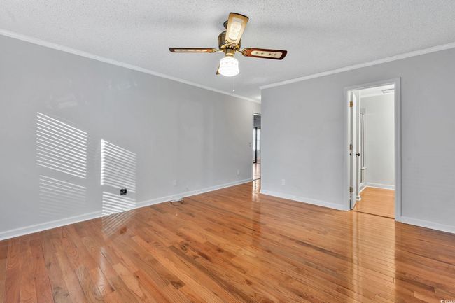 Unfurnished room with ceiling fan, light hardwood / wood-style floors, crown molding, and a textured ceiling | Image 9
