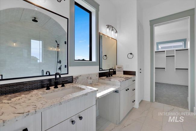 Full bath featuring a shower stall, marble finish flooring, two vanities, and a walk in closet | Image 29