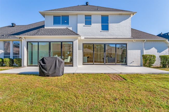 Rear view of property with brick siding, a lawn, roof with shingles, and a patio area | Image 33