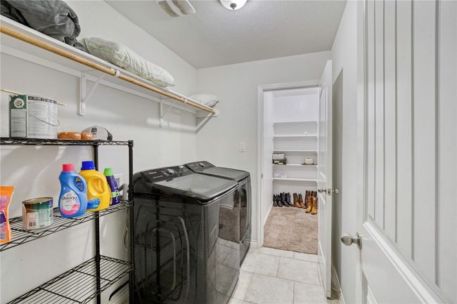 Laundry room with separate washer and dryer, light tile patterned floors, and a textured ceiling | Image 25