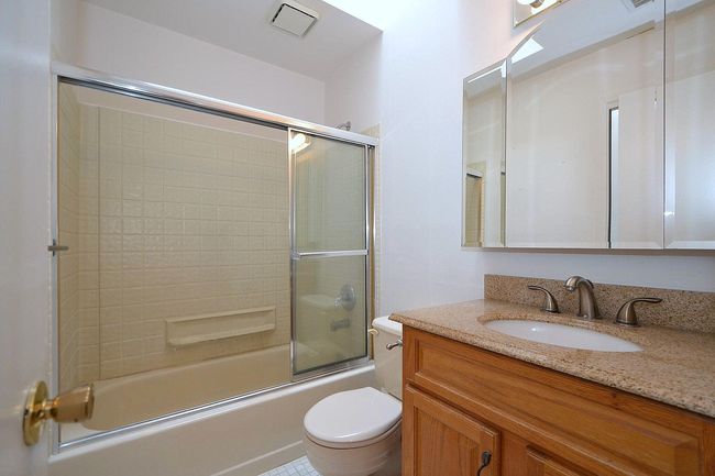 Bathroom with toilet, visible vents, bath / shower combo with glass door, and vanity | Image 14
