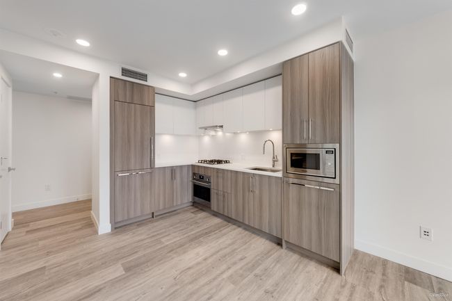 Kitchen featuring modern cabinets, appliances with stainless steel finishes, a sink, light countertops, and light wood finished floors | Image 14