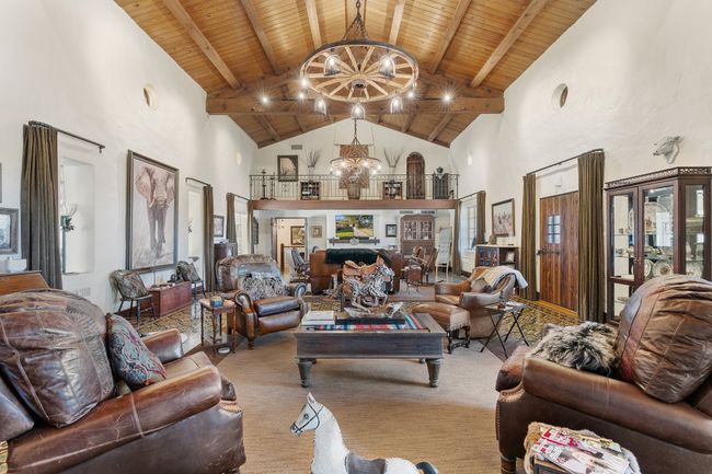 Carpeted living area featuring high vaulted ceiling, wood ceiling, beamed ceiling, and a chandelier | Image 12