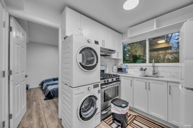 Laundry room featuring stacked washing machine and dryer and light wood finished floors | Image 25