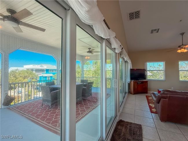 Doorway to outside with lofted ceiling, light tile patterned floors, visible vents, and a ceiling fan | Image 11