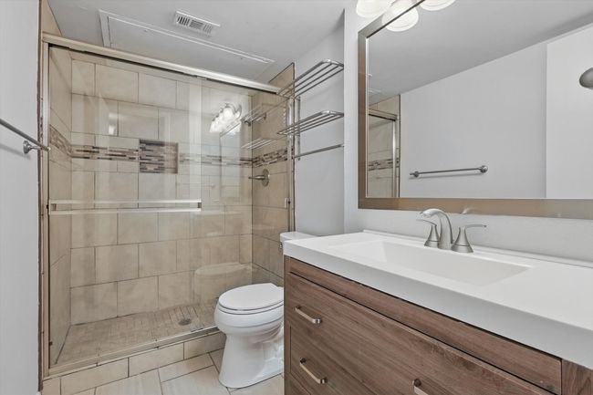 Bathroom featuring vanity, toilet, a shower stall, and tile patterned flooring | Image 6