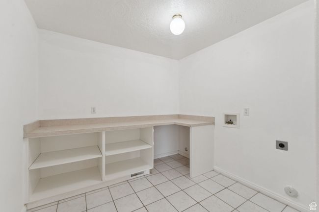 Laundry room featuring electric dryer hookup, washer hookup, a textured ceiling, and light tile patterned floors | Image 19