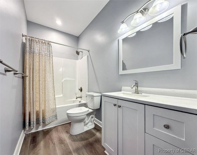 Full bath featuring wood finished floors, toilet, vanity, baseboards, and shower / bath combo with shower curtain | Image 18