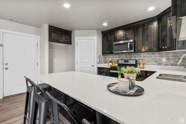 Kitchen featuring stainless steel appliances, a sink, backsplash, recessed lighting, and wood finished floors | Image 17