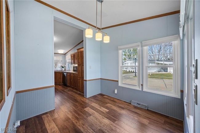 Unfurnished dining area with dark wood-type flooring, wainscoting, and vaulted ceiling | Image 11