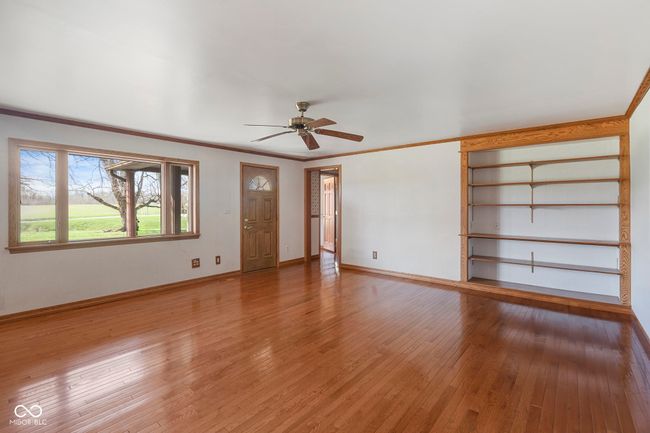 unfurnished living room with a ceiling fan, light wood-type flooring, baseboards, and ornamental molding | Image 15