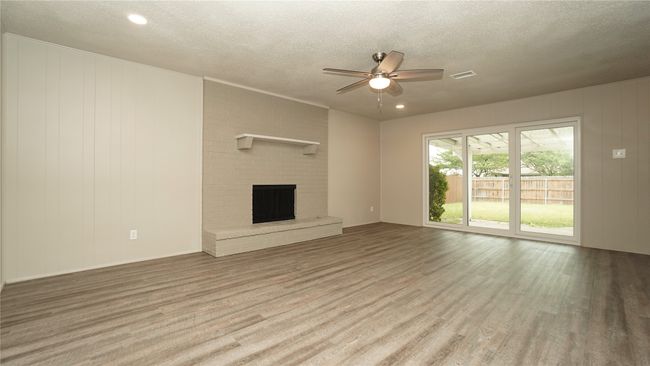 The large family room features a lighted ceiling fan, luxury vinyl plank flooring, a cozy wood-burning fireplace, recessed lighting, and views of the backyard. Low-e sliding doors were recently installed | Image 5