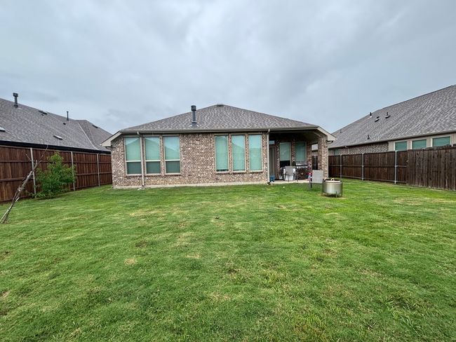 Rear view of property with brick siding, a fenced backyard, and a patio | Image 14