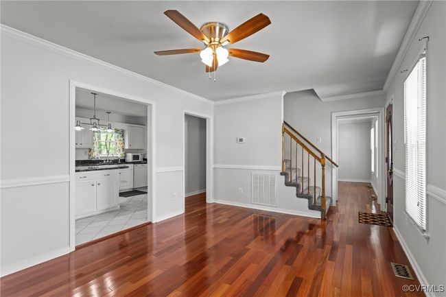 Unfurnished living room featuring stairway, light wood-style floors, and visible vents | Image 9