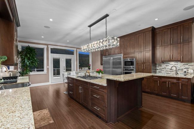 Kitchen with a sink, built in appliances, a center island, and dark wood finished floors | Image 9