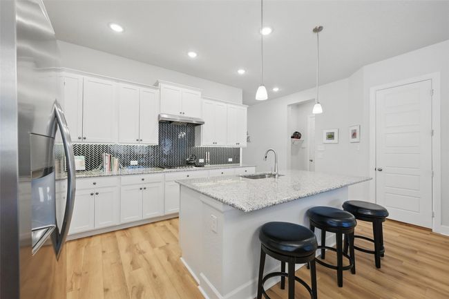 Kitchen with appliances with stainless steel finishes, a sink, light wood-style floors, decorative backsplash, and under cabinet range hood | Image 5