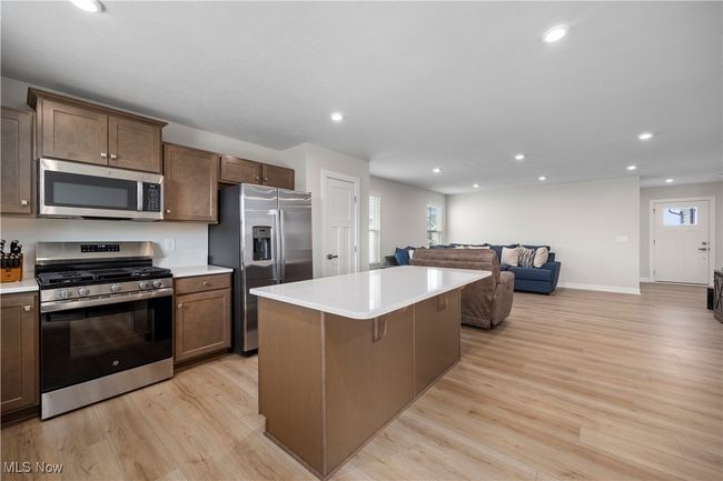Kitchen with a center island, open floor plan, light countertops, light wood finished floors, and stainless steel appliances | Image 19
