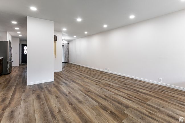 Unfurnished living room featuring dark wood finished floors, baseboards, recessed lighting, and a chandelier | Image 6